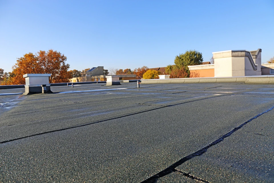 Toiture commerciale plate avec membrane d'étanchéité bitumineuse, système de drainage et éléments techniques