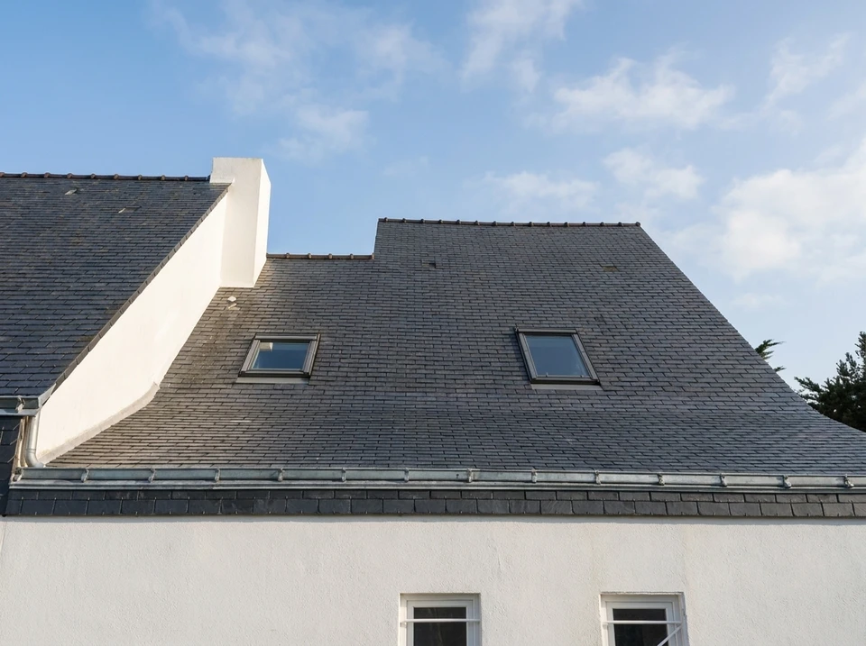 Façade extérieure d'une maison moderne avec toiture en tuiles canal terre cuite et gouttière métallique apparente